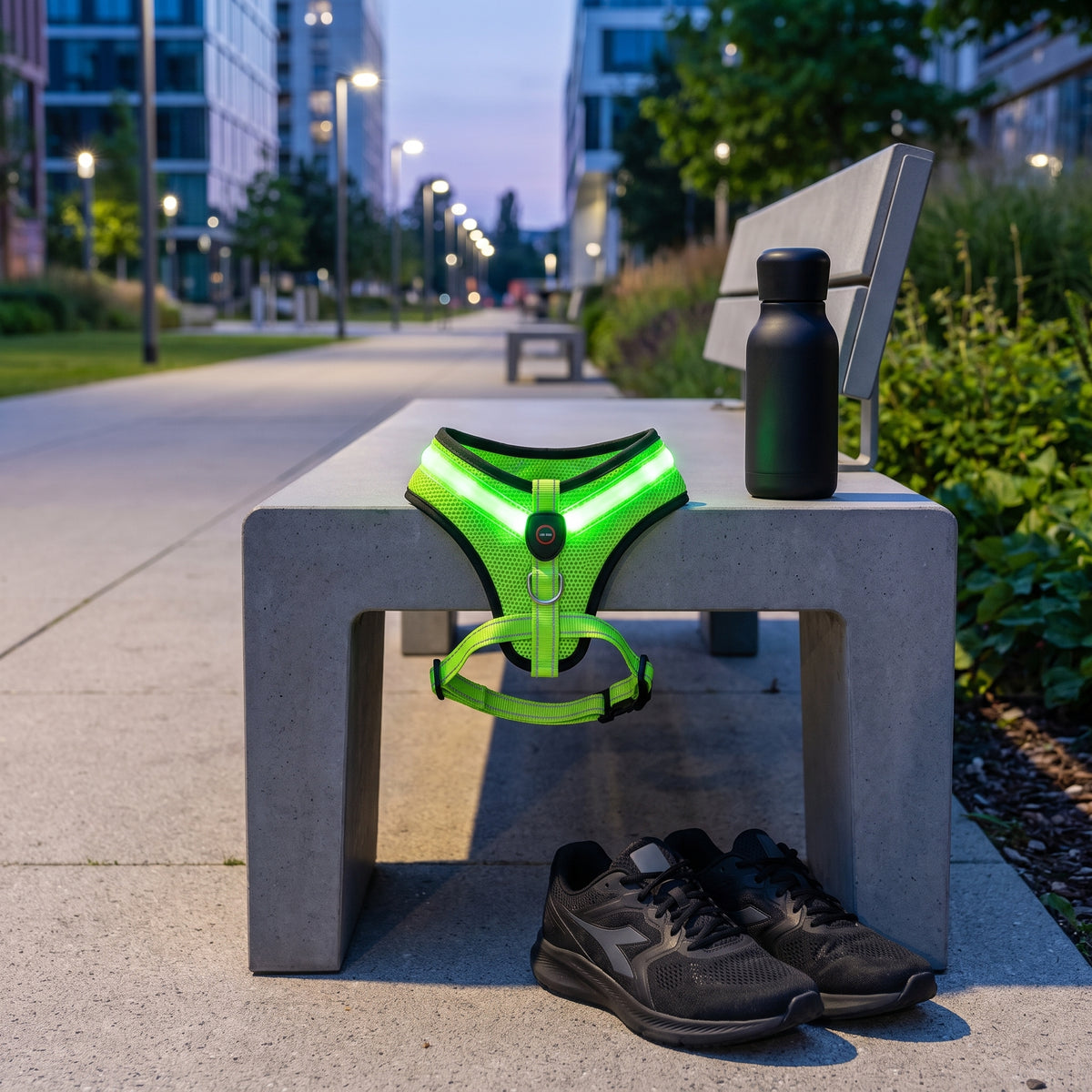 Green GlowPup LED dog harness displayed on a park bench